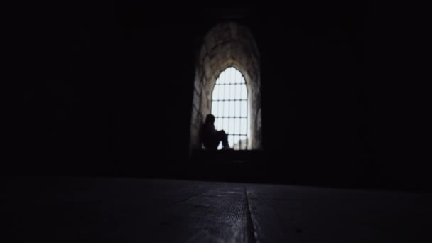 Siluetti tyttö istuu kaltereiden takana tornissa ja koskettaa kalterit kädellään
 - Materiaali, video