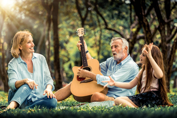 Happy family play guitar and sing together in park - Photo, Image
