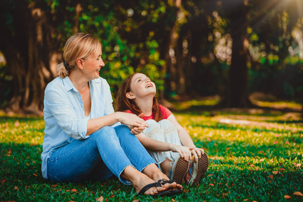 Zrelaksowany szczęśliwą matką i córeczkę dziecko w parku na świeżym powietrzu. Koncepcja rodzicielstwa i dziecko. - Zdjęcie, obraz
