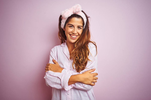 Молодая красивая женщина в пижаме стоит на розовом изолированном фоне счастливое лицо улыбается со скрещенными руками, глядя в камеру. Позитивный человек
. - Фото, изображение