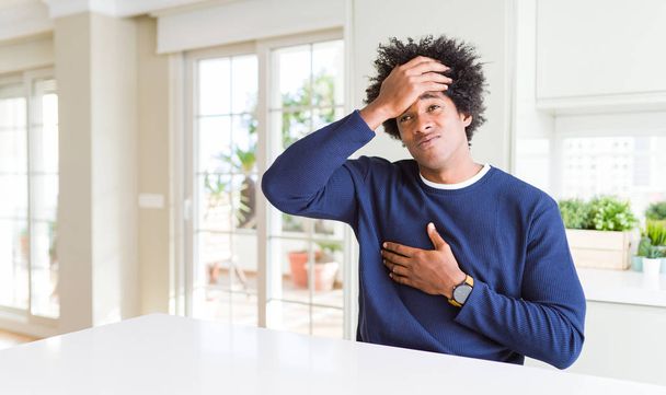 Young african american man wearing casual sweater sitting at home Touching forehead for illness and fever, flu and cold, virus sick - Фото, зображення