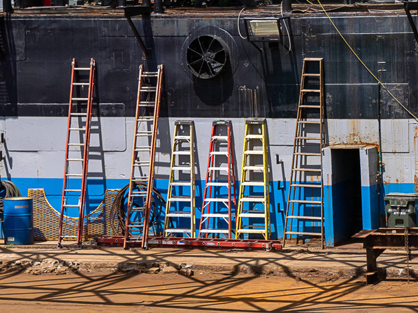 шість драбин, що лежать на боці корабля в гавані
 - Фото, зображення