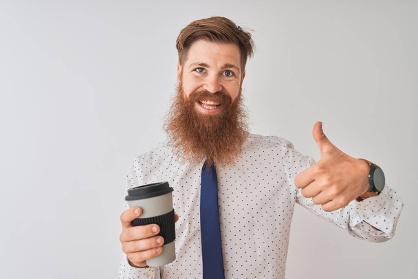 Nuori punapää irlantilainen mies juo ottaa pois kahvia seisoo eristetty valkoinen tausta onnellinen iso hymy tekee ok merkki, peukalo ylös sormilla, erinomainen merkki
 - Valokuva, kuva