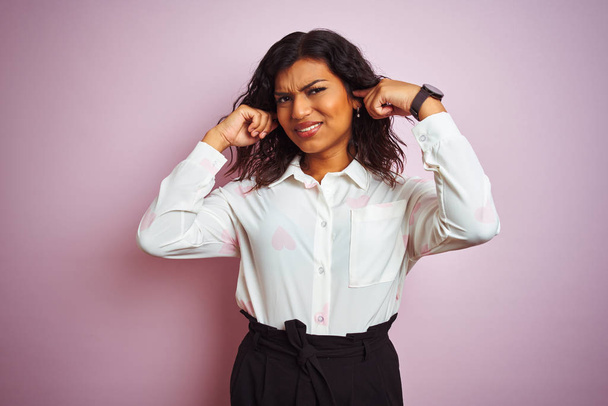 Transsexual transgender businesswoman standing over isolated pink background covering ears with fingers with annoyed expression for the noise of loud music. Deaf concept. - Photo, Image
