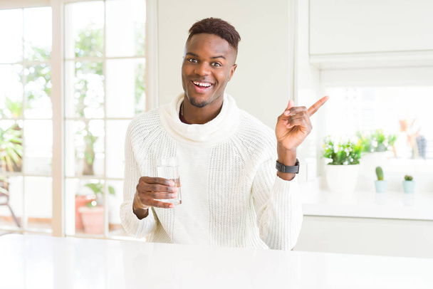 アフリカ系アメリカ人の男性は、手と指を横に指差して非常に幸せな水の新鮮なガラスをドライク - 写真・画像