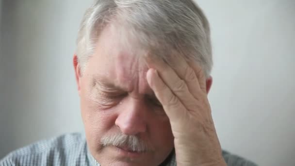 ein älterer Mann massiert seine Schläfe, als er unter starken Kopfschmerzen leidet - Filmmaterial, Video