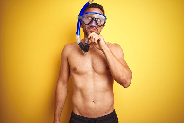 Young handsome shirtless man wearing diving goggles over isolated yellow background serious face thinking about question, very confused idea - Fotoğraf, Görsel