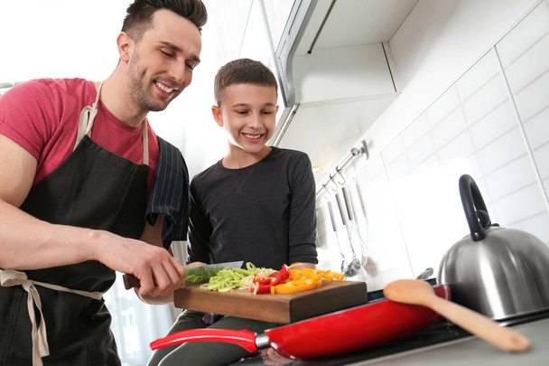 Dad and son cooking together in kitchen - Foto, afbeelding