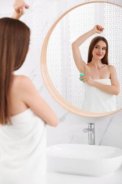 Beautiful young woman applying deodorant after shower in bathroom - Фото, зображення