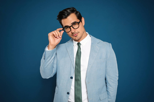 Portrait of handsome young businessman wearing glasses on blue background - Foto, Imagem