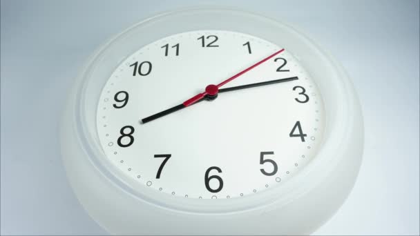 Zbliżenie biały zegar ścienny, czarny zegar ręce chodzić na białym tle, koncepcja czasu. - Materiał filmowy, wideo