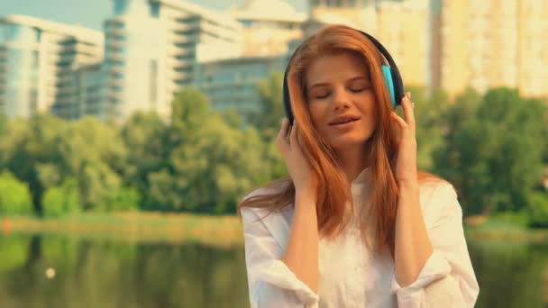 front view redhead girl listen music outdoors - Footage, Video