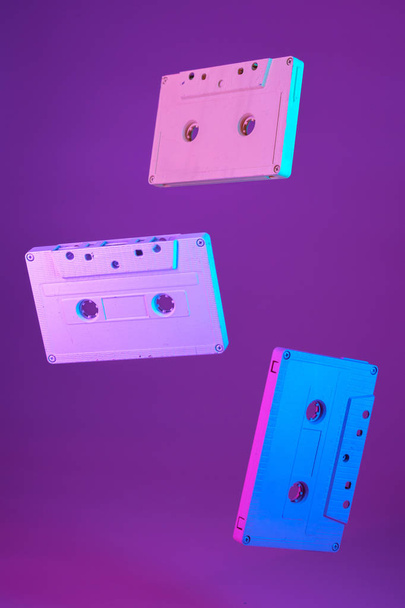 Cassette tape vintage style suspended in air on purple background - Fotoğraf, Görsel
