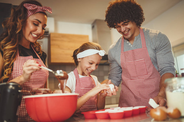 Fiatal szülők lánya konyhában Muffin tészta készül - Fotó, kép