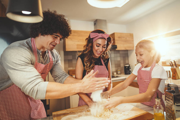Young family with daughter cooking pizza in kitchen at home - Photo, Image