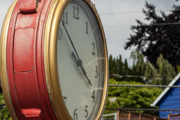 relógio ao ar livre vermelho e dourado contra fundo natural na cidade
 - Foto, Imagem