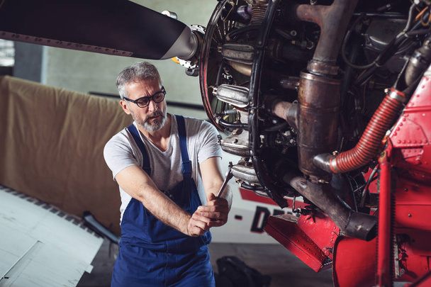 Aircraft maintenance mechanic inspects plane engine - Foto, afbeelding