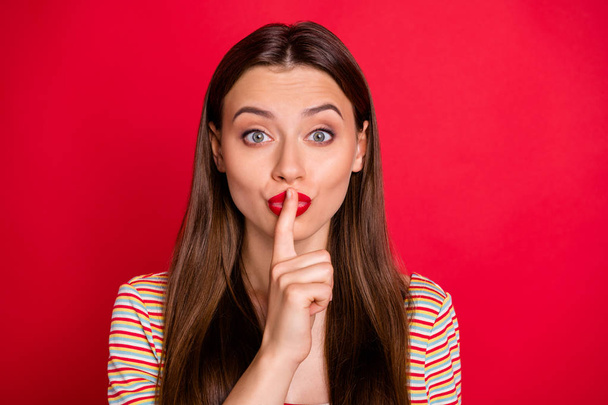 Photo of pretty lady holding finger on lips ask to stop talking wear casual outfit isolated burgundy background - 写真・画像