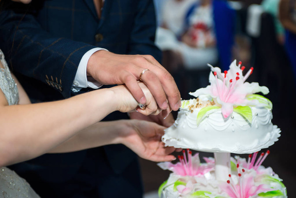 para trzymała ręce, aby wyciąć pierwszy kawałek, piękne i pyszne, tort weselny dla swoich ukochanych rodziców - Zdjęcie, obraz