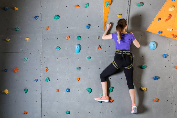 Mujer joven escalando pared en el gimnasio
 - Foto, imagen