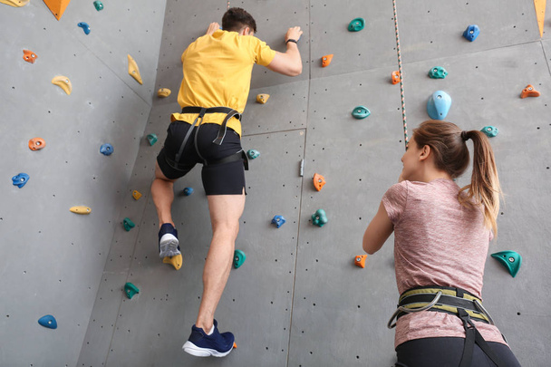 Spor salonunda duvar tırmanma eğitmeni ile genç adam - Fotoğraf, Görsel