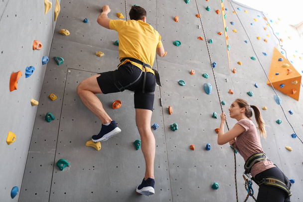 Молодий чоловік з інструктором скелелазіння стіни в спортзалі
 - Фото, зображення