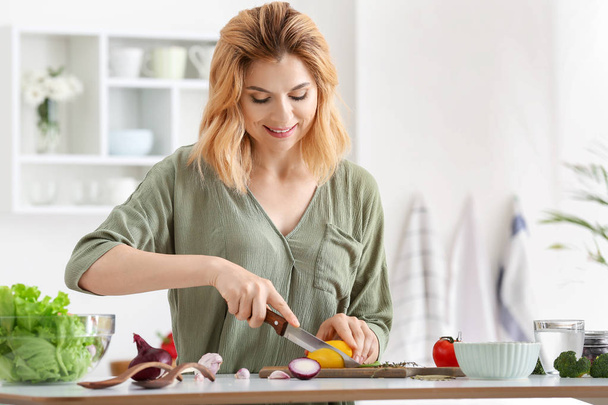 Woman making healthy vegetable salad in kitchen - Zdjęcie, obraz