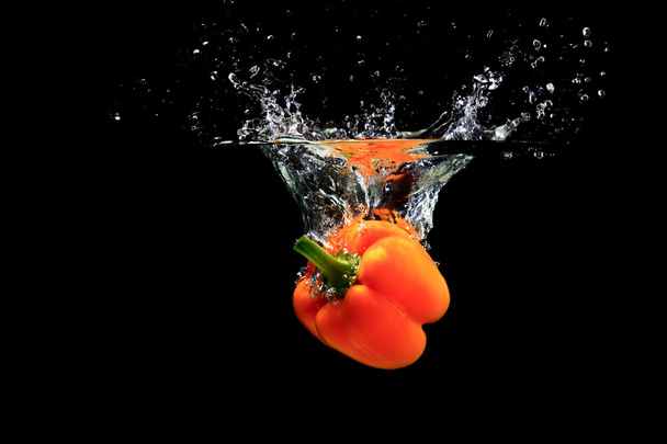 Orange peppers splashing water - 写真・画像