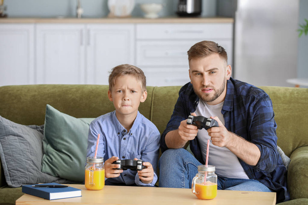 Portrait de père et fils jouant à un jeu vidéo à la maison
 - Photo, image