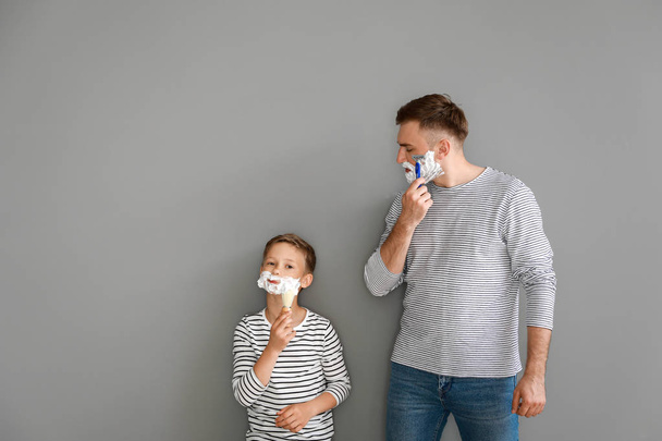 Father and his little son shaving against grey background - Photo, Image