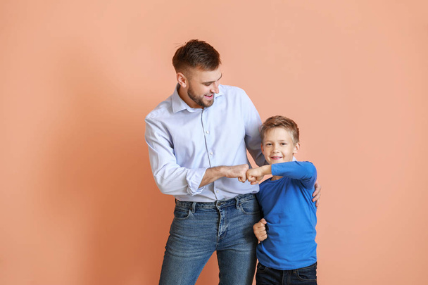 Vater und sein kleiner Sohn stoßen mit Fäusten gegen farbigen Hintergrund - Foto, Bild