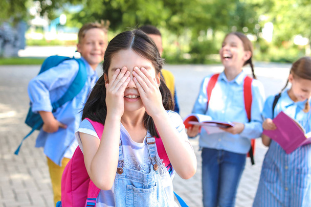 Маленькая школьница закрывает глаза руками на улице
 - Фото, изображение