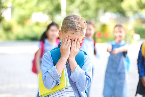 Запуганный маленький мальчик с агрессивными одноклассниками на улице
 - Фото, изображение