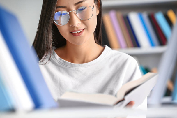 junge asiatische Studentin wählt Bücher in Bibliothek - Foto, Bild