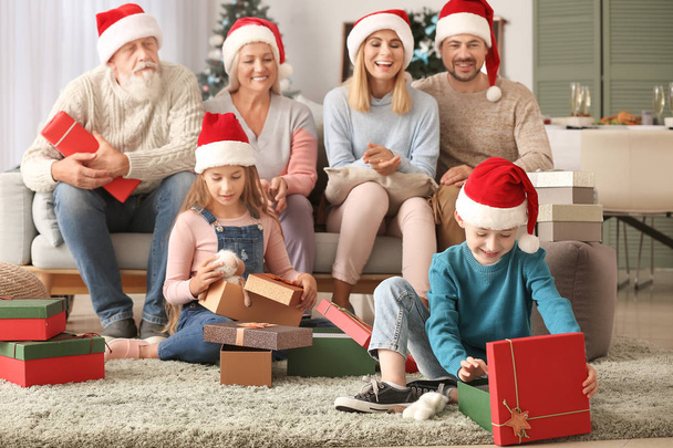 Маленькие дети со своей семьей открывают рождественские подарки дома
 - Фото, изображение