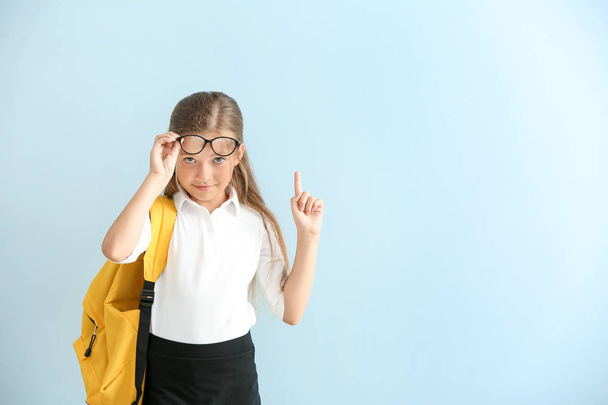 Маленька школярка з піднятим індексним пальцем на кольоровому фоні
 - Фото, зображення