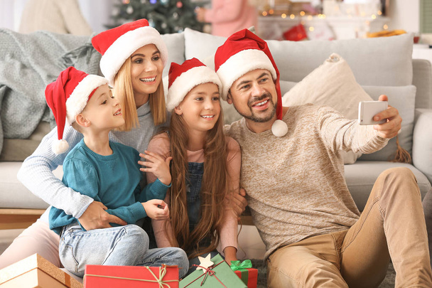 Ευτυχισμένη οικογένεια με τα Χριστουγεννιάτικα δώρα παίρνοντας selfie στο σπίτι - Φωτογραφία, εικόνα