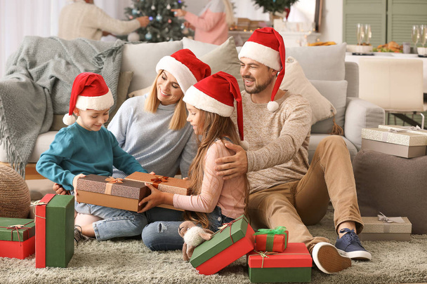 Familia feliz con cajas de regalo en la habitación decorada para Navidad
 - Foto, Imagen