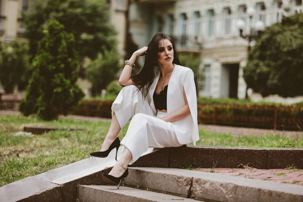 beautiful brunette woman with long hair in a white suit and lace top - Zdjęcie, obraz
