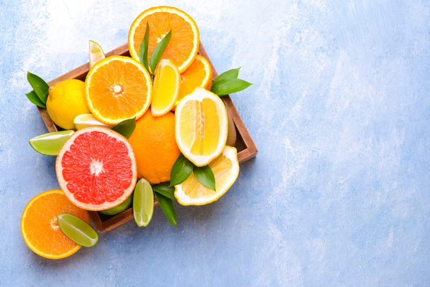 Коробка з різними цитрусовими фруктами на кольоровому фоні
 - Фото, зображення