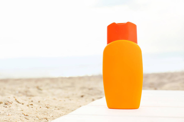 Bottle of sunscreen cream on sand beach - Fotó, kép