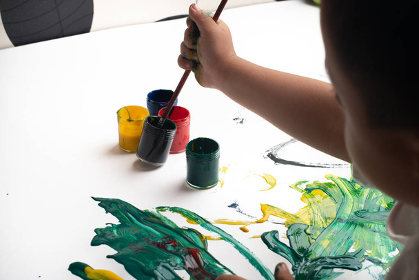 Hände eines kleinen Jungen malen mit Aquarellen auf weißem Papier - Foto, Bild