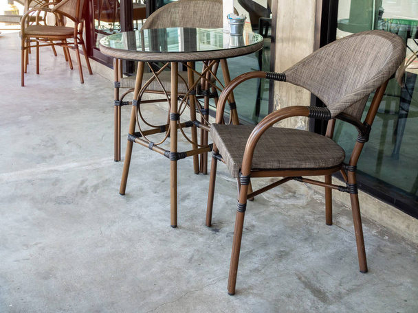 Cadeiras castanhas modernas e mesa de vidro redonda perto de parede de vidro outsid
 - Foto, Imagem