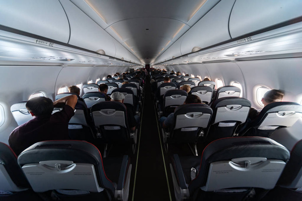 Airplane cabin seats with passengers. Economy class of new cheapest low-cost airlines without delay or cancellation of flight. Travel trip to another country. - Photo, Image