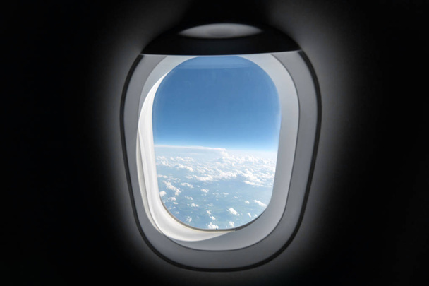 Airplane window view to cloudy sky and earth. Beautiful landscape from aircraft cabin. Flying without fear of flying, incidents and turbulence. - Photo, Image