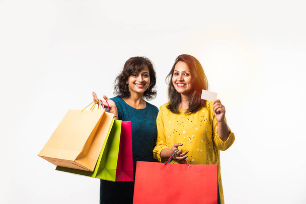 Indian Mother daughter sisters shopping with colourful bags, standing isolated over white background - Photo, Image