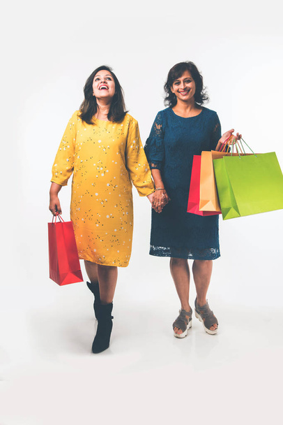 Indian Mother daughter sisters shopping with colourful bags, standing isolated over white background - Foto, Imagem