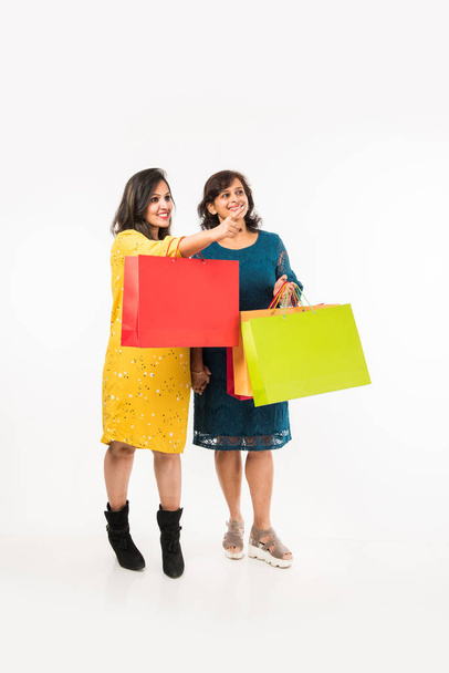 Indian Mother daughter sisters shopping with colourful bags, standing isolated over white background - Fotoğraf, Görsel