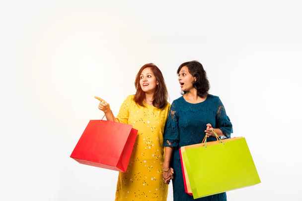 インドの母娘姉妹ショッピングとともにカラフルなバッグ、立って隔離された白い背景 - 写真・画像