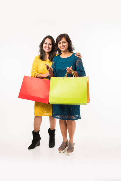 Indian Mother daughter sisters shopping with colourful bags, standing isolated over white background - Photo, Image